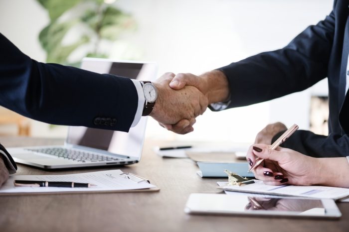 A photograph of a handshake over a desk.