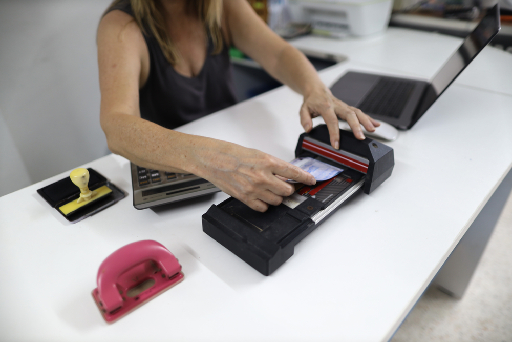 A photograph of someone using an old credit card machine.